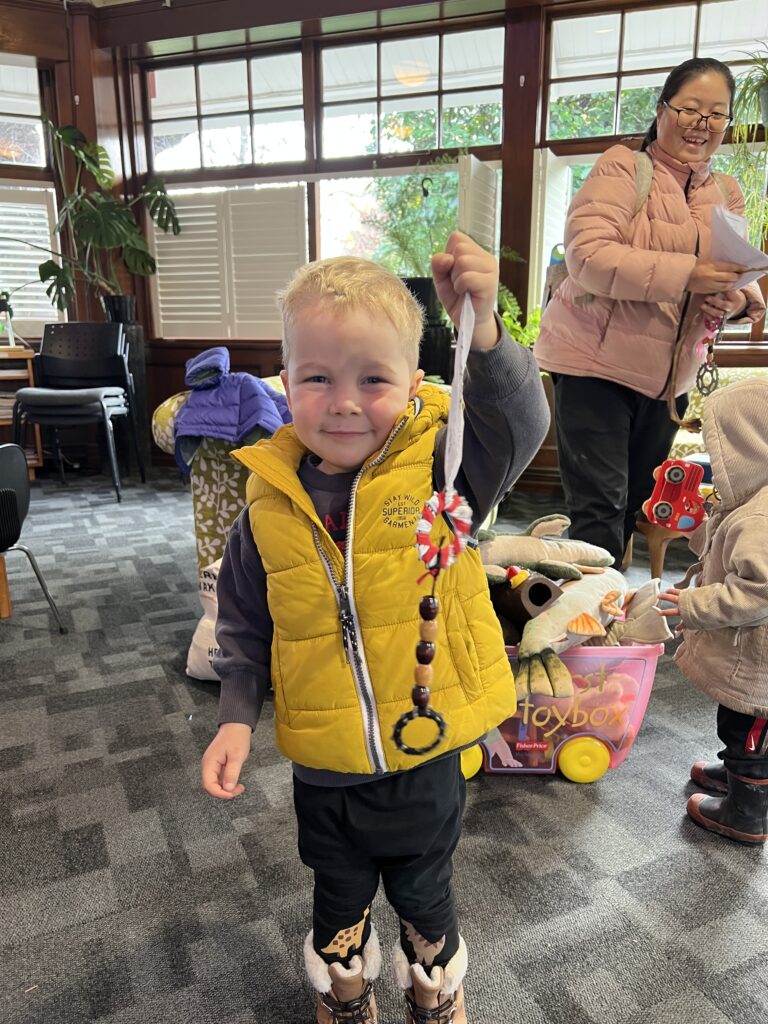 A young boy proudly showing his handmade craft project at an Envirokids event.
